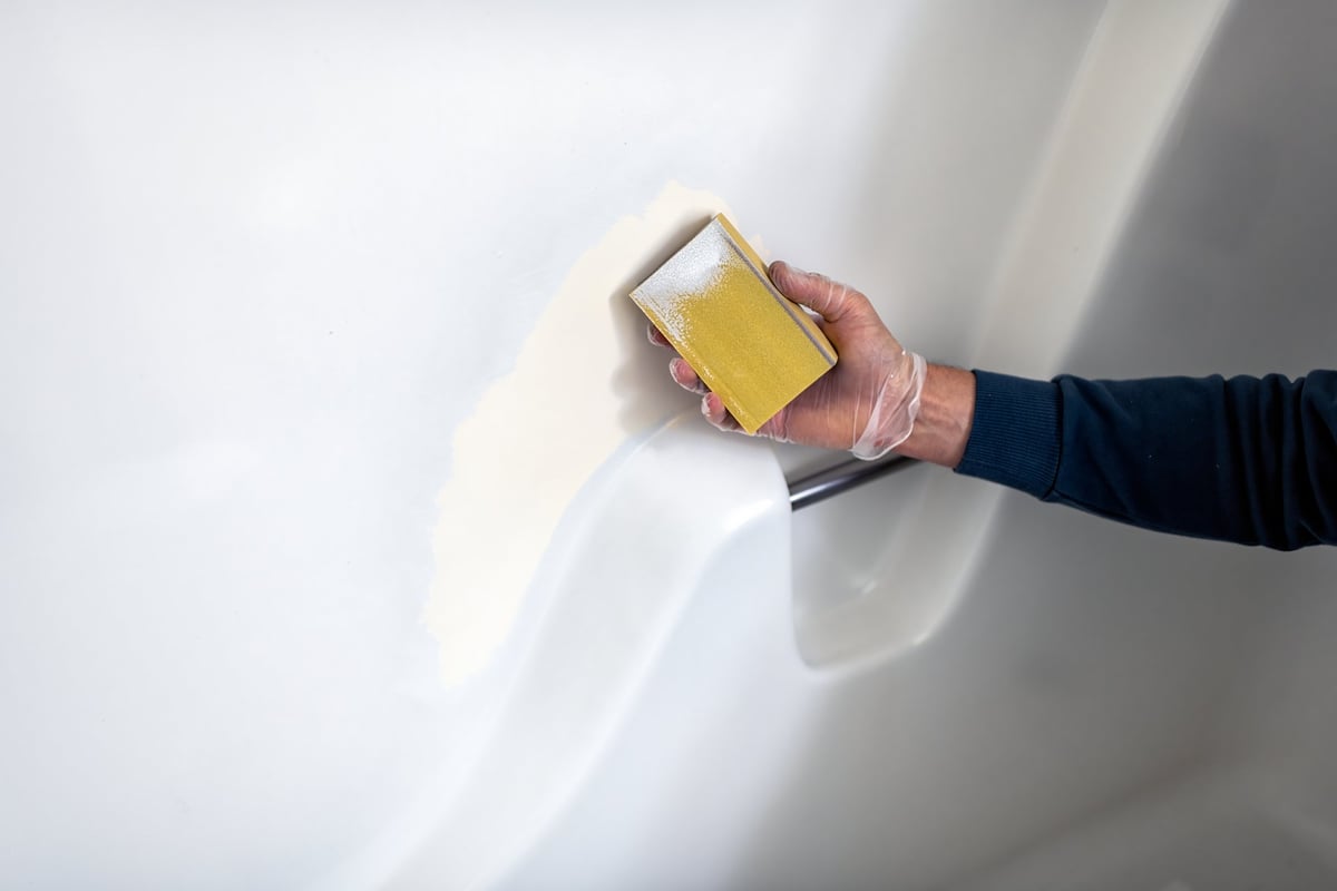 Professional refinishing a bathtub by hand during resurfacing