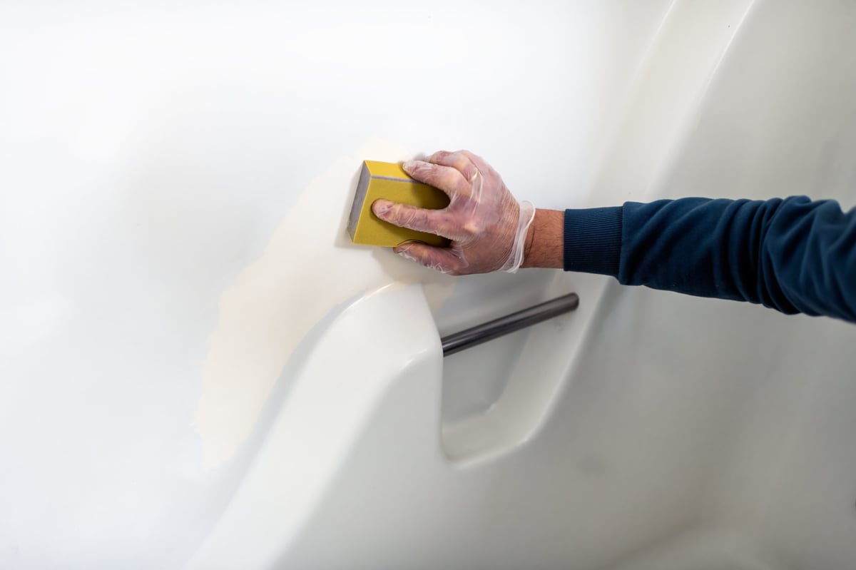 Technician carefully resurfacing a bathtub